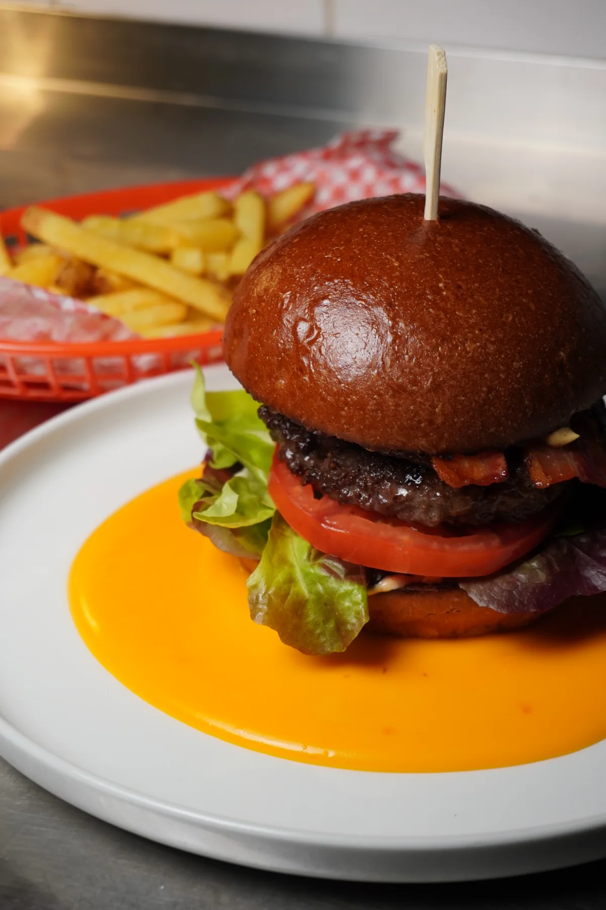 Detail burgeru s čedarovou omáčkou, salátem a rajčetem