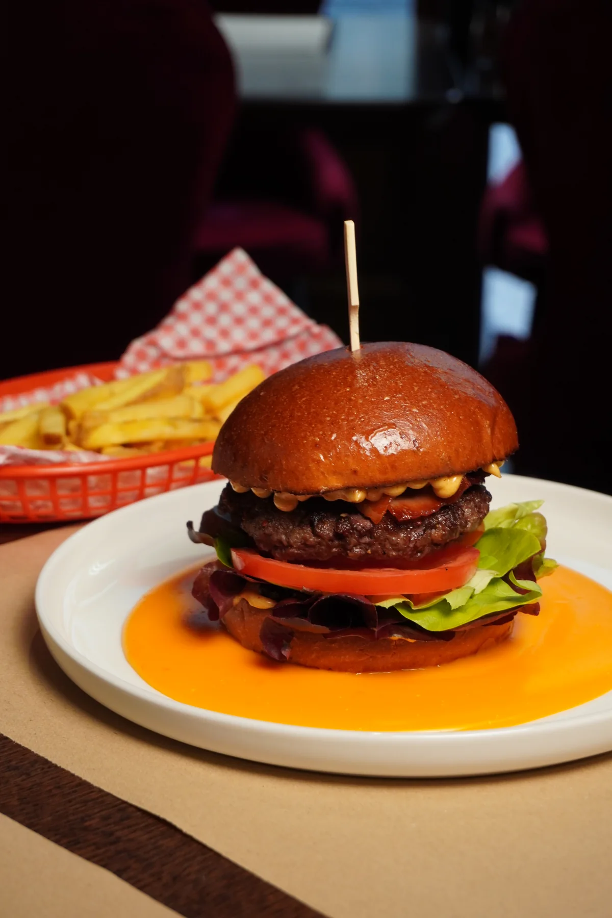 Burger s čedarovou omáčkou a hranolky podávaný u stolu